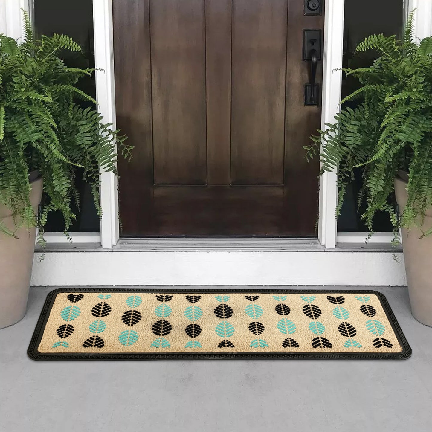 A beige floor mat with a leaf pattern placed on the floor in front of a door, flanked by two potted plants.