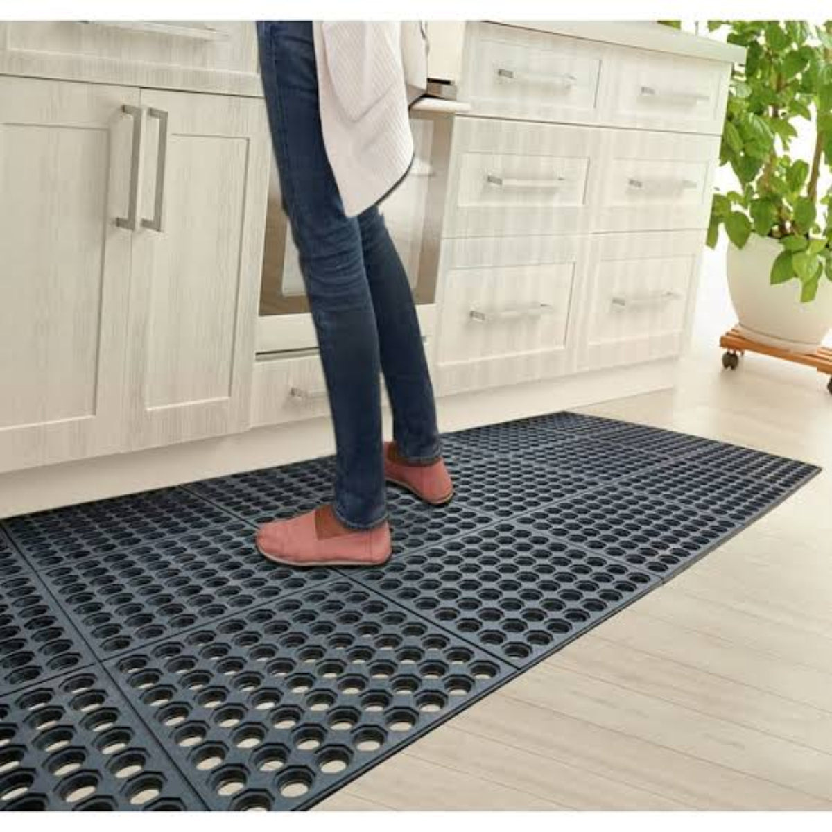 Person standing on a black mat in a kitchen.