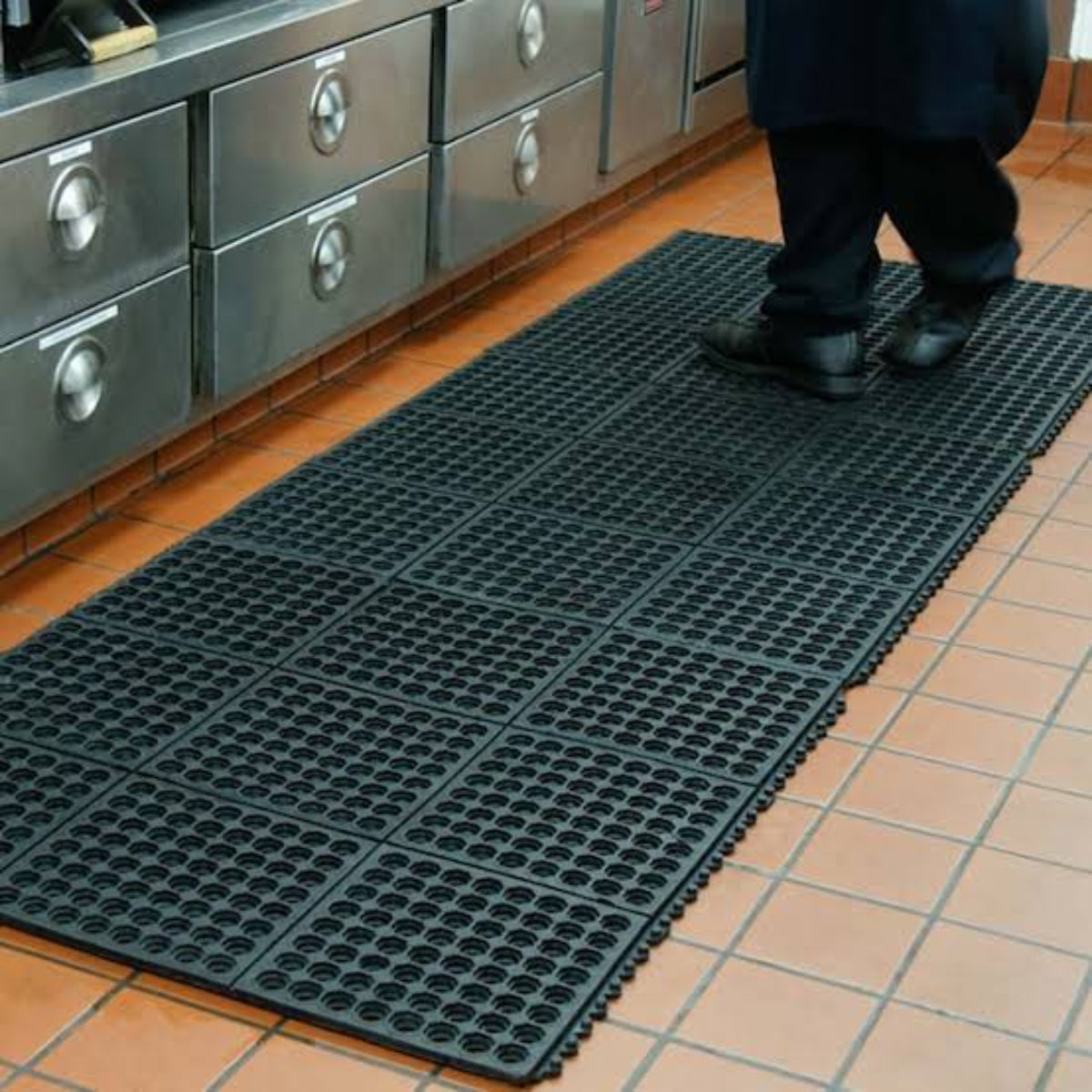 Person standing on a black textured rubber mat in a kitchen.