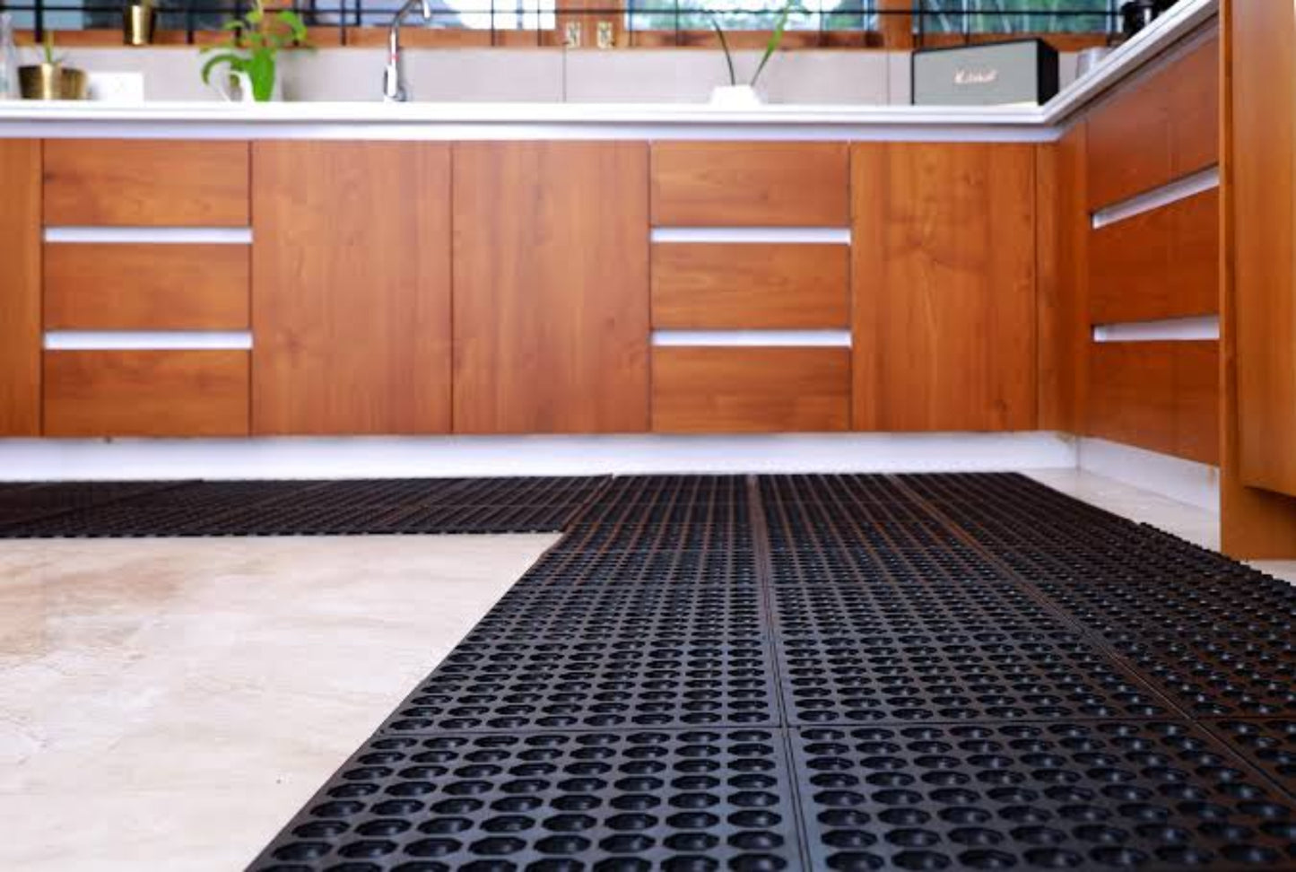 Modern kitchen with wooden cabinets and a black textured rubber floor mat.