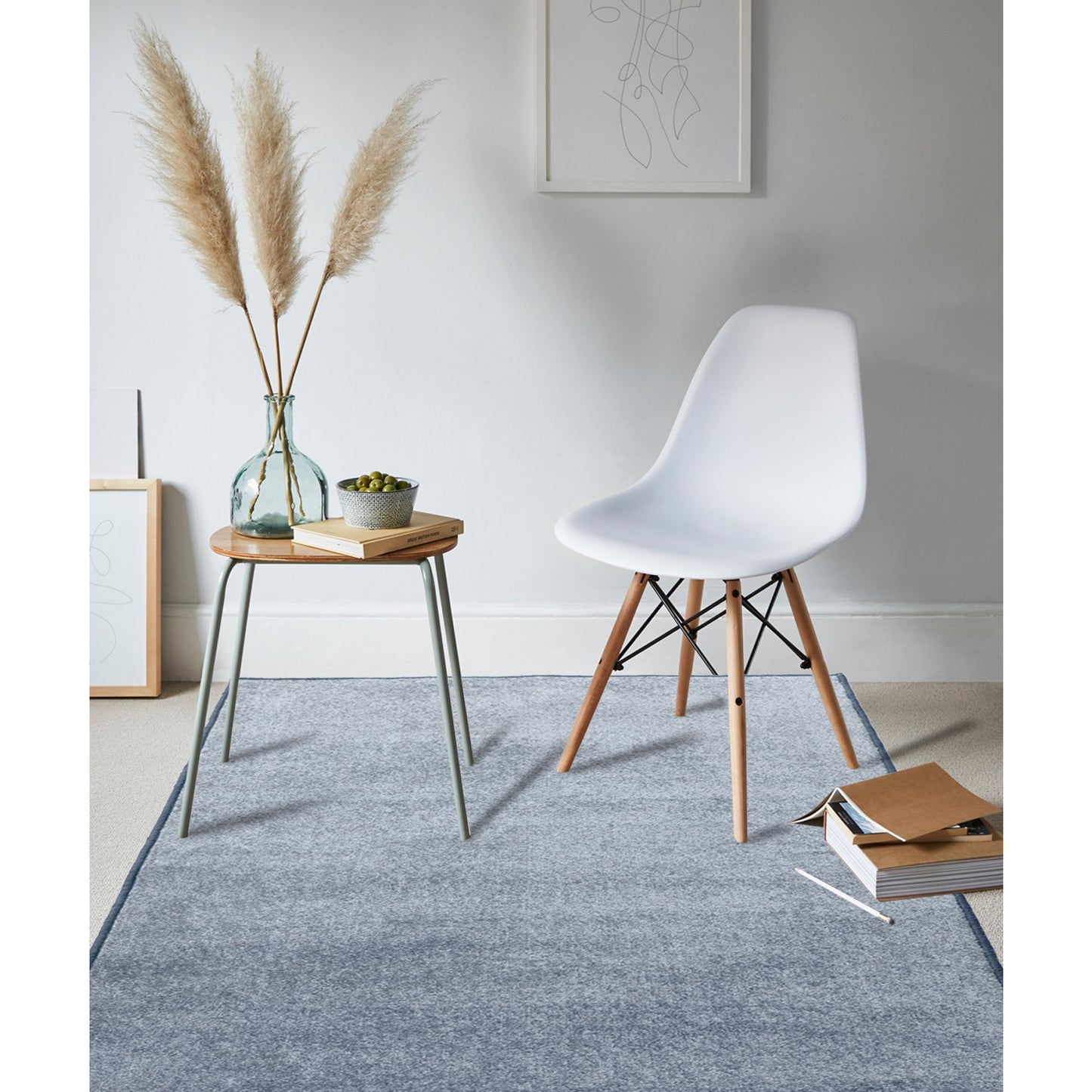 A rectangular, solid grey anti-slip entrance mat made of polypropylene material, displayed in a living room setting with a white chair and a wooden side table with a decorative item on top.
