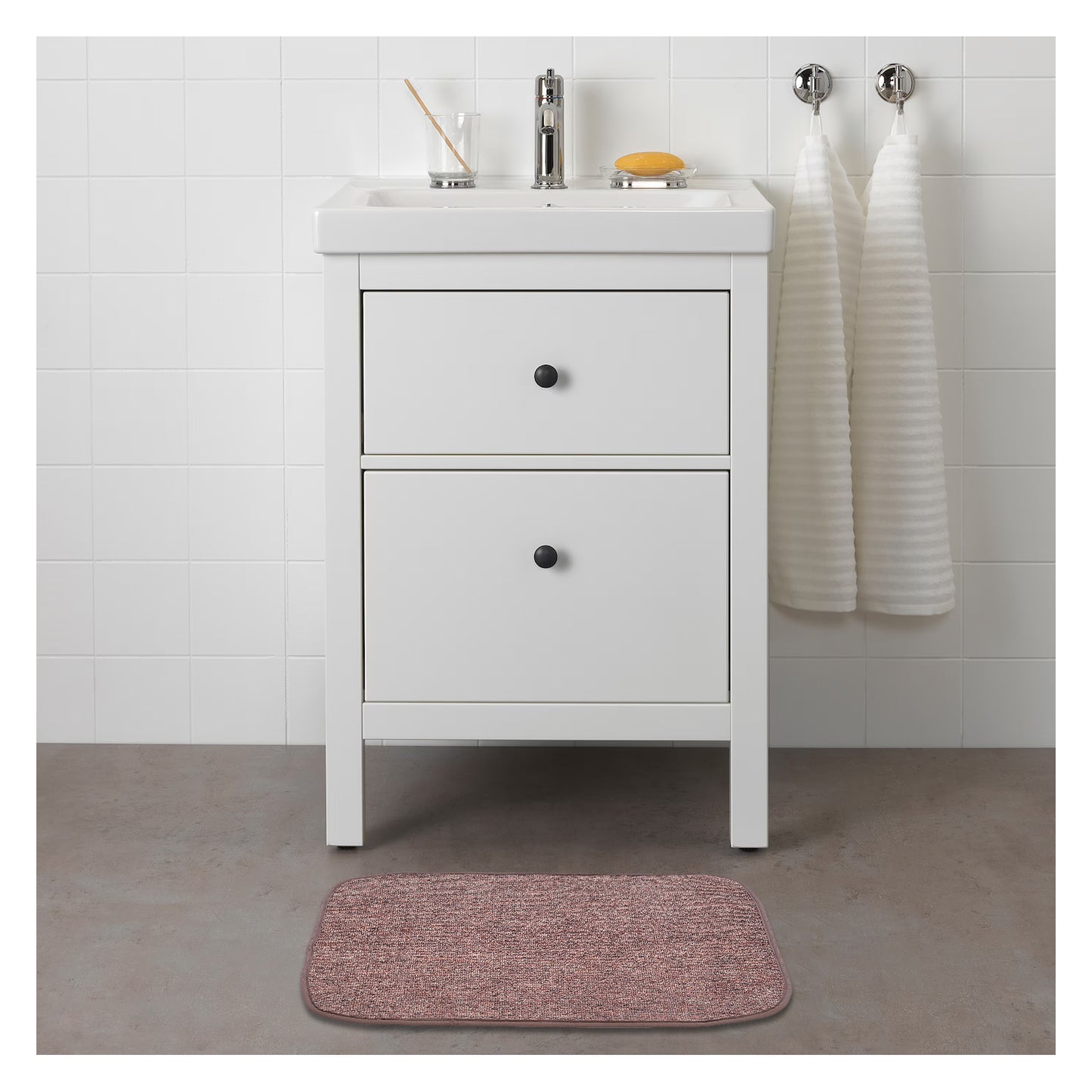 A plain brown rectangular mat placed on the floor in front of a white bathroom vanity.