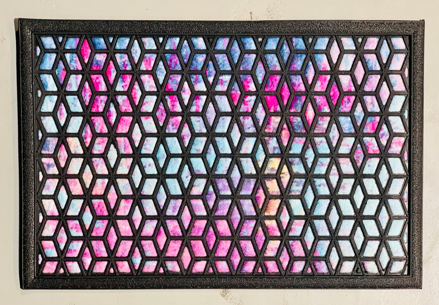 A black rectangular doormat with a geometric pattern of arrows and intersections, featuring a reflective surface and a solid black border.