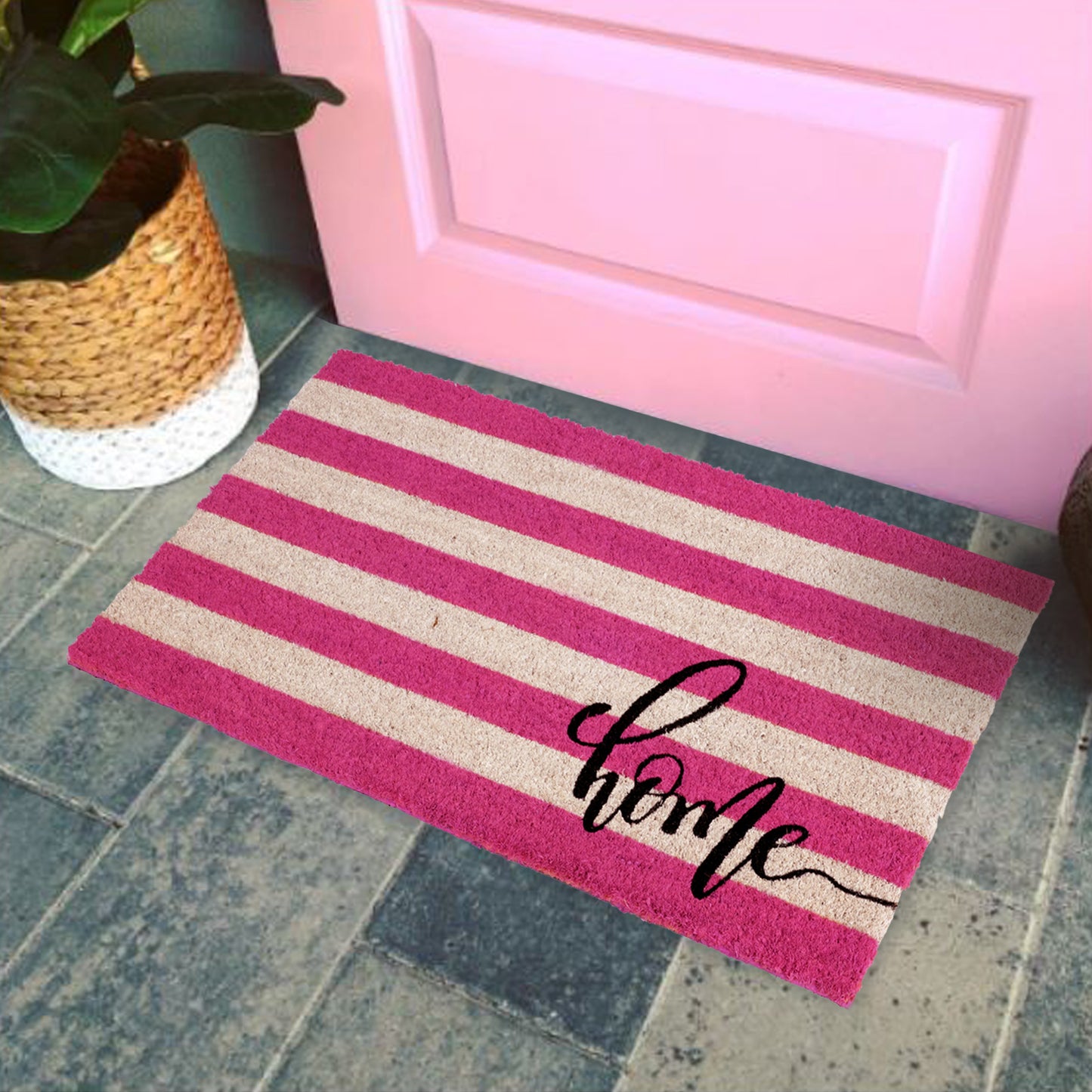 A rectangular natural coir door mat with a retro stripe design in pink and white, featuring the word 'Home' in a cursive script, placed on a doorstep.
