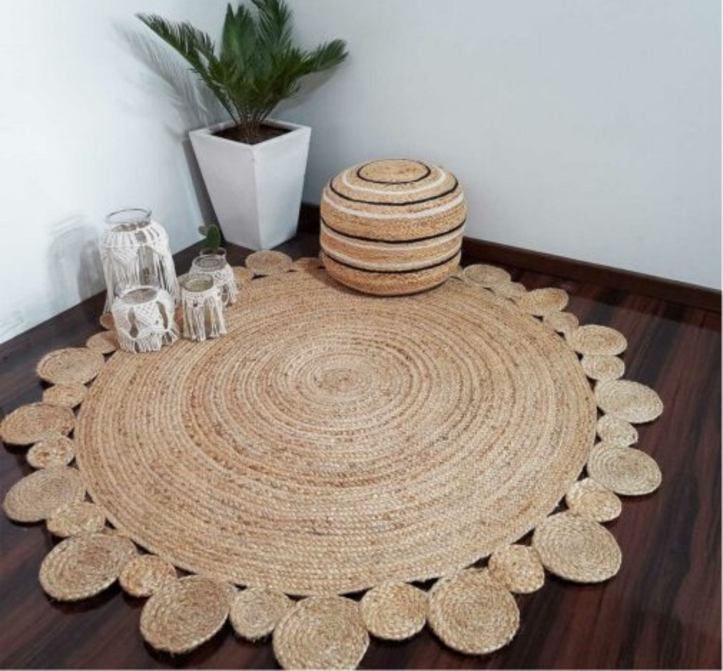 Round woven jute rug on a wooden floor with decorative items and a plant.