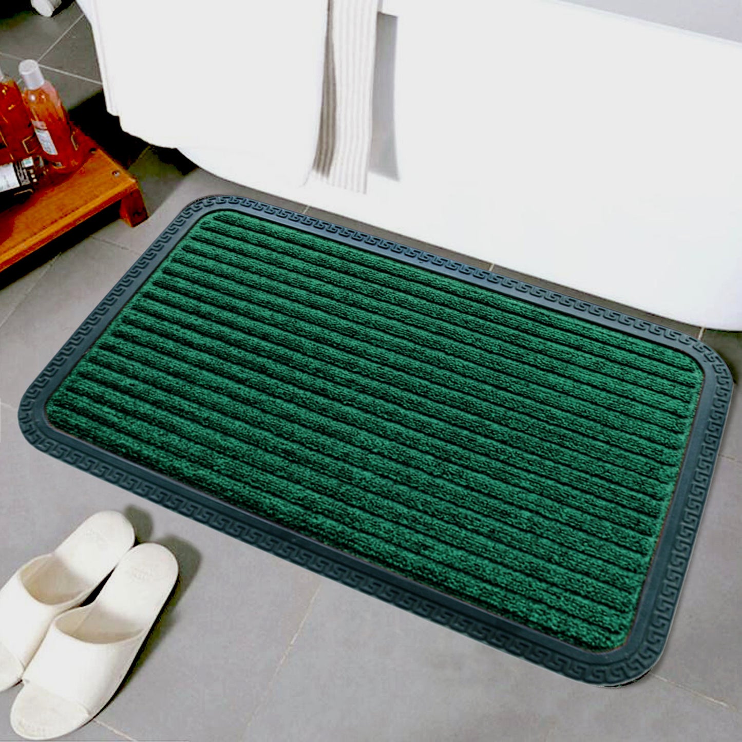 A green striped OnlyMat QuickDry Anti Slip mat placed on a tiled floor next to a white door and a pair of slippers, with a window in the background.