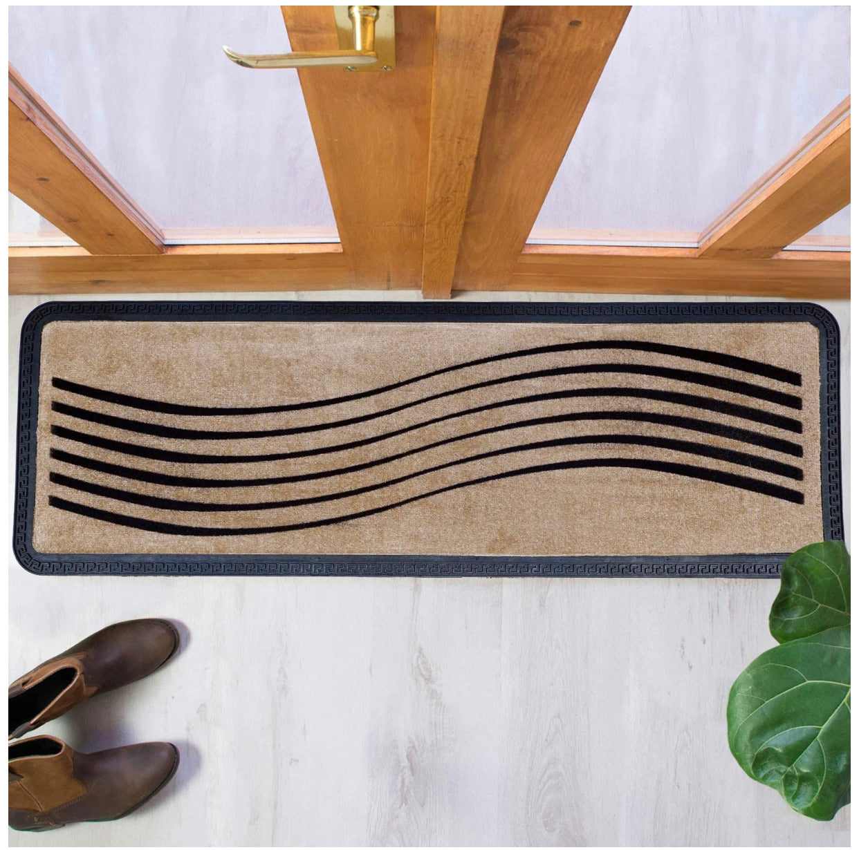 A beige oblong floor mat with a wavy pattern, placed on the floor in front of a door, with a pair of shoes at the bottom of the image and a plant to the side.