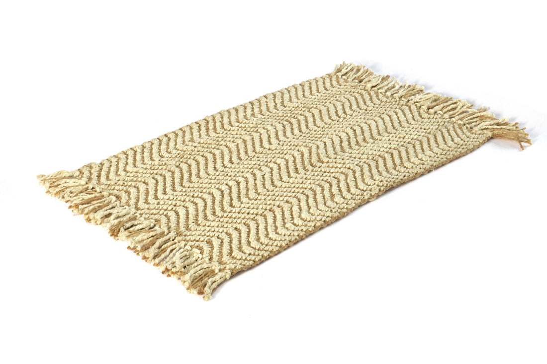 A beige hand-woven jute rug with a herringbone pattern on a white background.