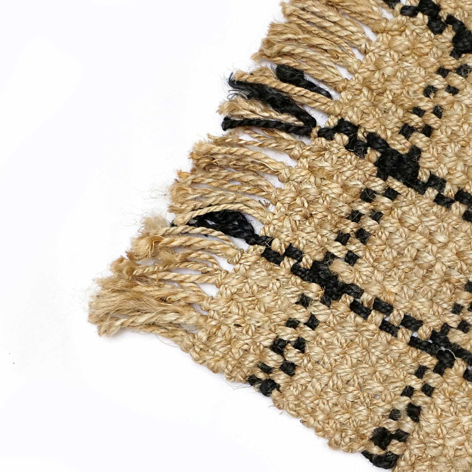 Close-up of a woven jute mat with black geometric patterns on a white background