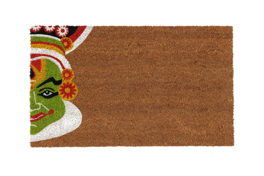 A rectangular coir doormat with a traditional Onam festival design featuring a kathakali character's face in green, red, and white.