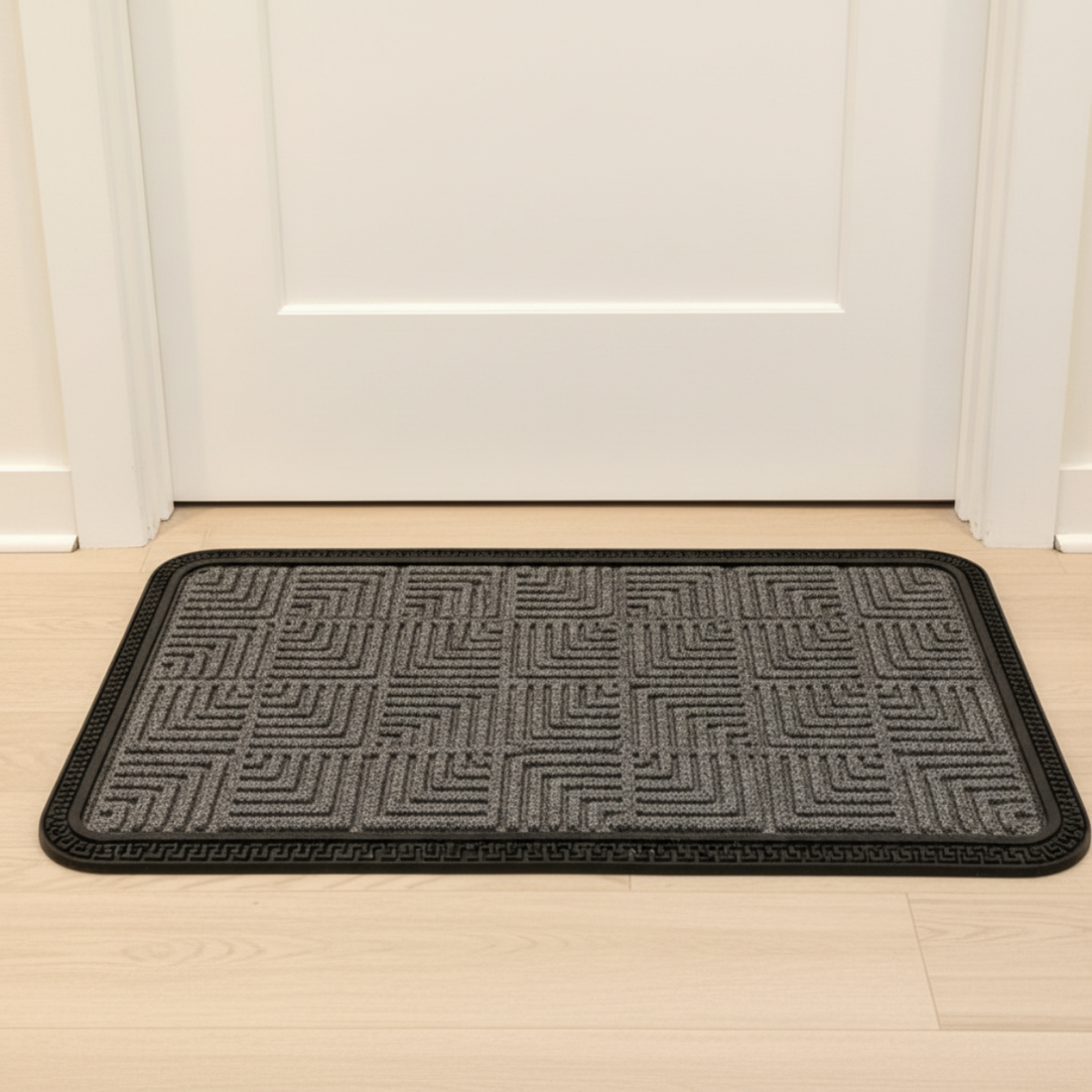 Textured doormat with geometric pattern on a wooden floor in front of a white door.