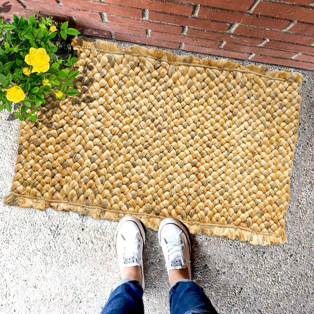 A hand-braided jute rug in beige colour, placed on the ground with a pair of sneakers at the top of the image, indicating the texture and size of the rug.