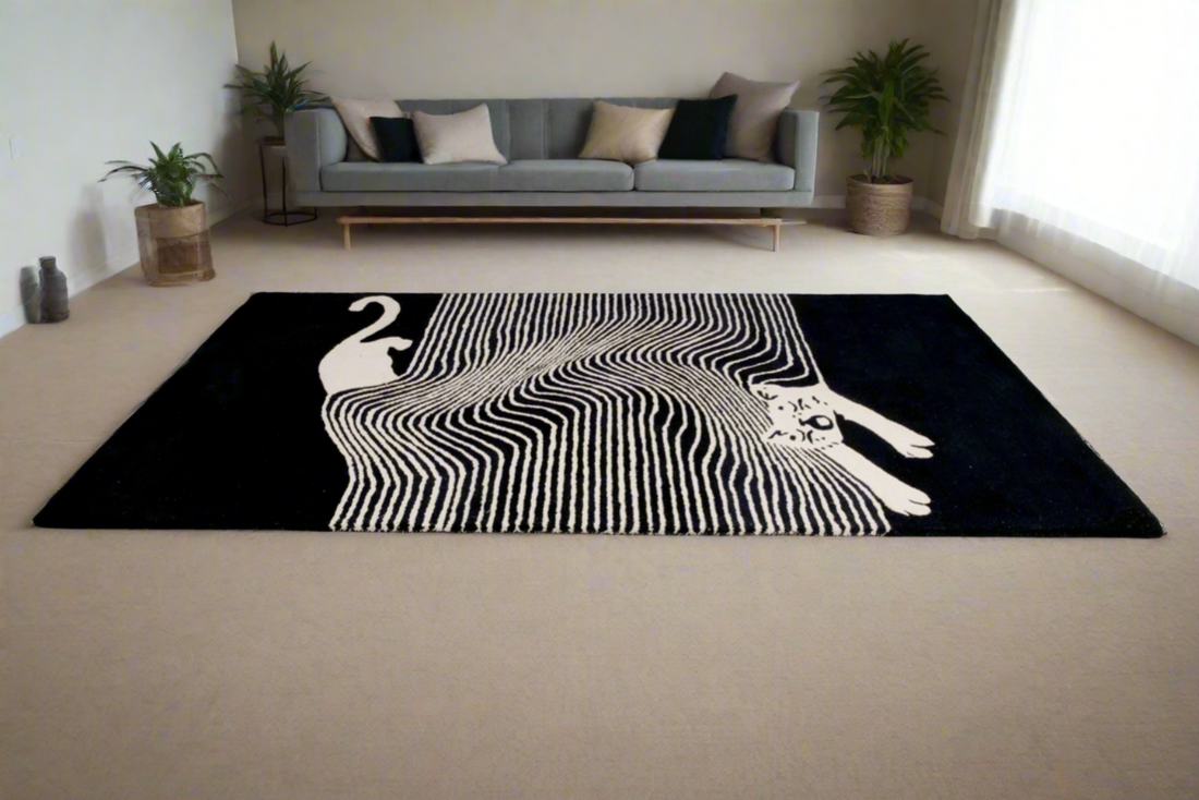 A modern black and white rug with a geometric cat design, placed on a floor in a living room setting with a sofa and plants in the background.