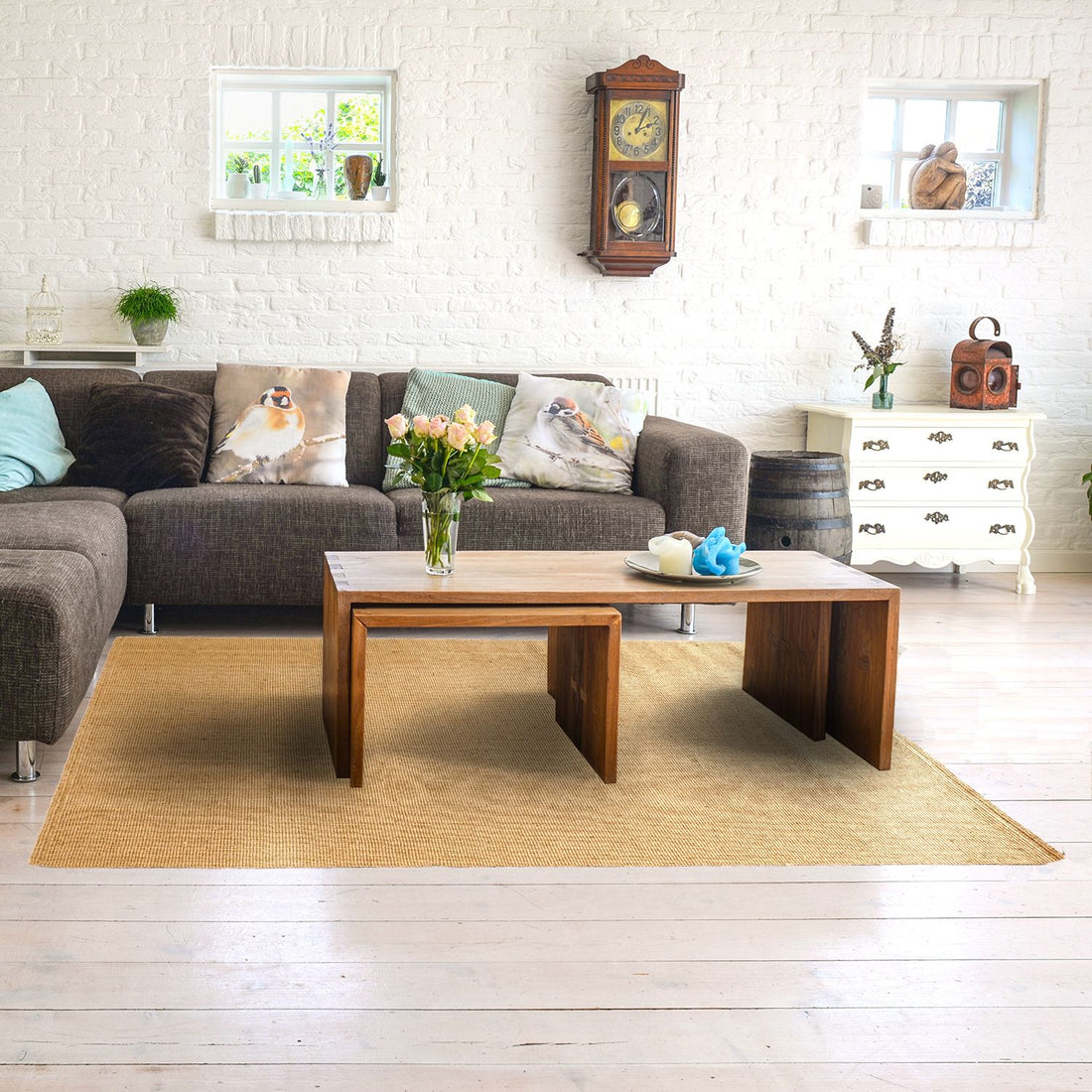 A jute rug with a lean yarn weave pattern in a natural colour, placed on a wooden floor in a cosy living room setting with a couch, pillows, and a wooden coffee table in the background.