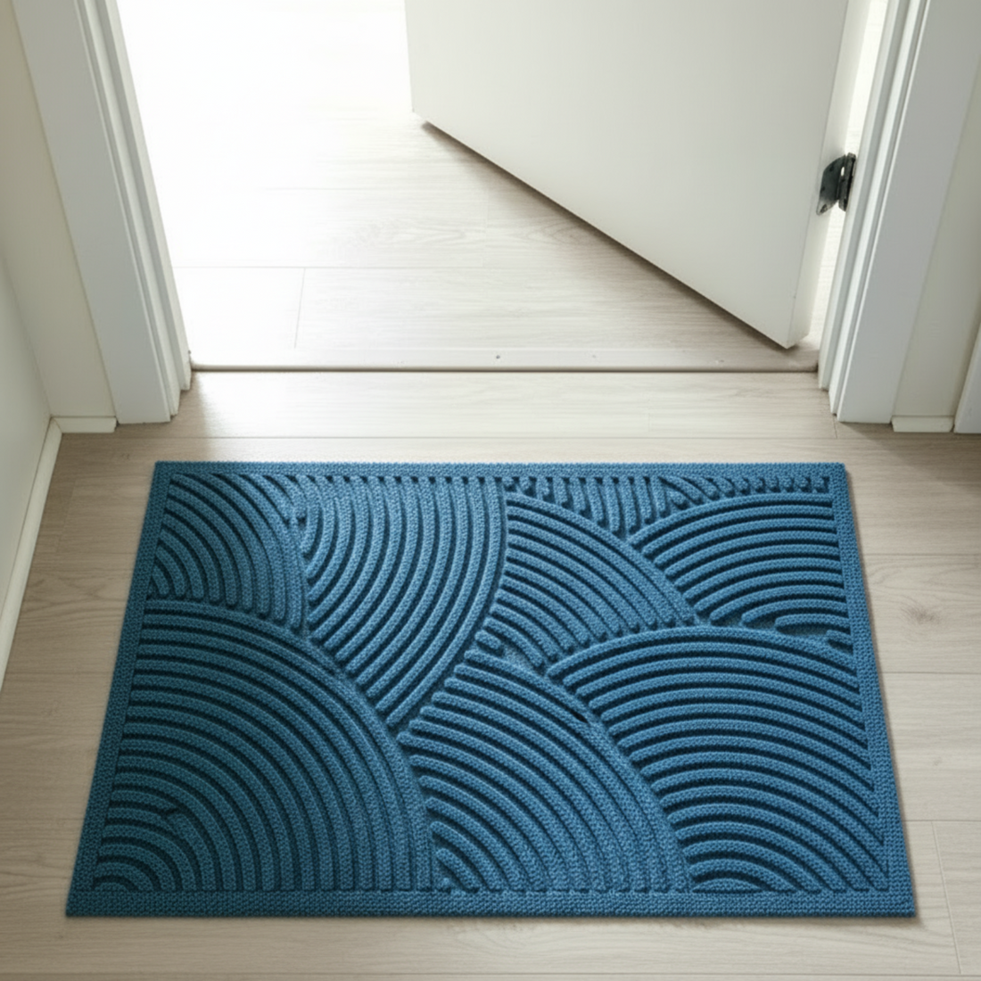 Blue textured doormat on a wooden floor with a white door in the background