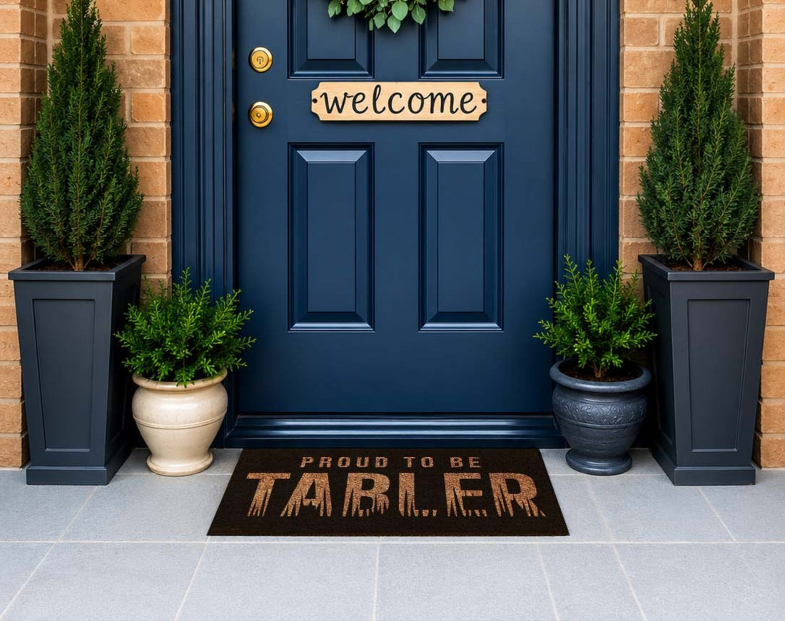 Blue front door with 'Welcome' sign, potted plants, and 'Proud to be Tabler' doormat.