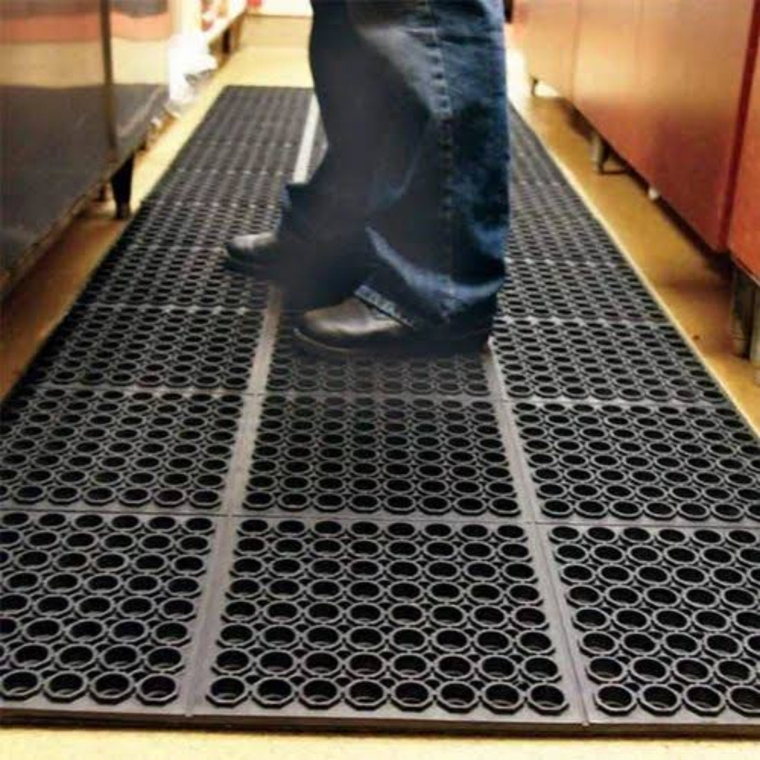 
                      
                        A person walking on a black perforated rubber mat in a store.
                      
                    