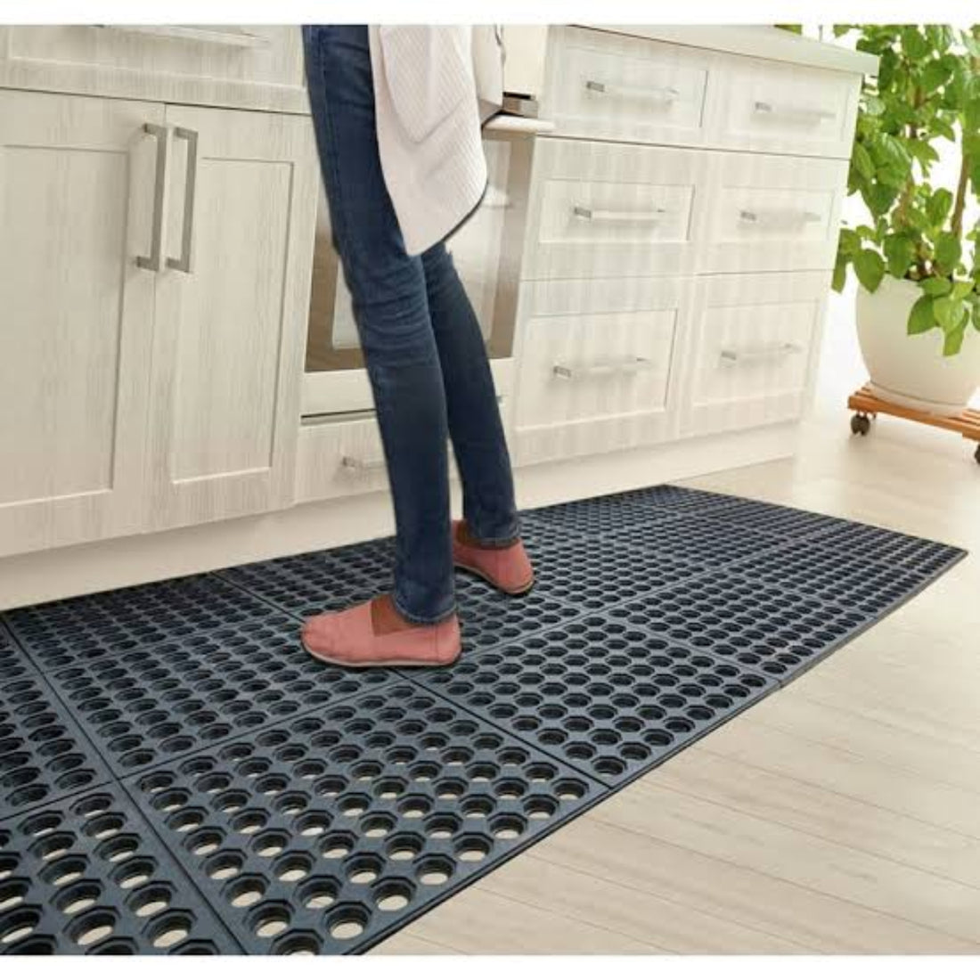 Person standing on a black mat in a kitchen.