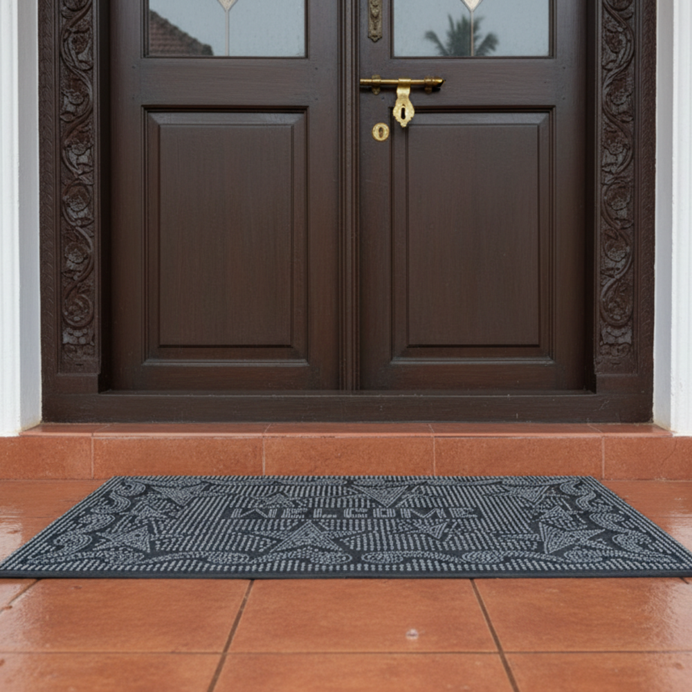 Black rubber pin doormat with a geometric pattern in front of a brown door