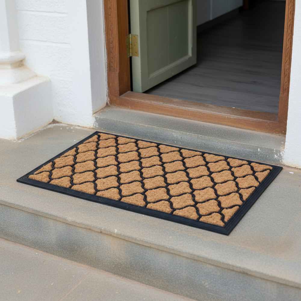 Doormat with geometric pattern on a concrete step outside a building.
