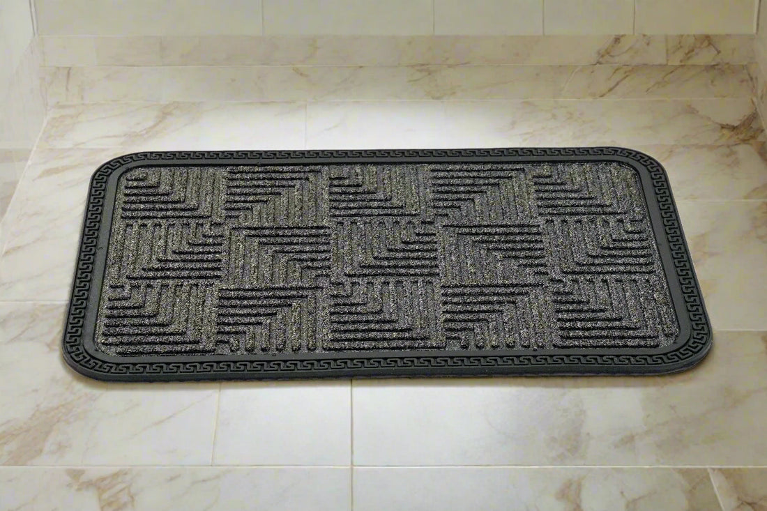 A dark grey rectangular bath mat with a geometric step design.