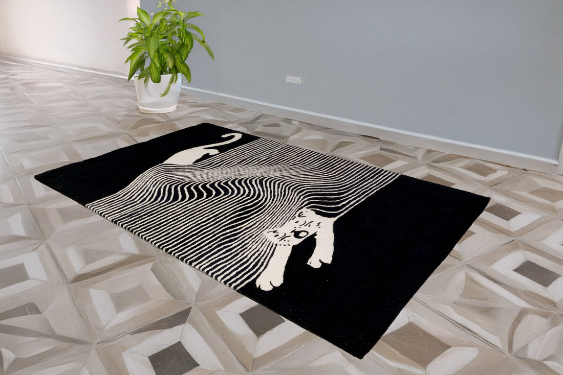 A modern geometric patterned black and white bamboo silk rug displayed on a tiled floor with a cat silhouette design.