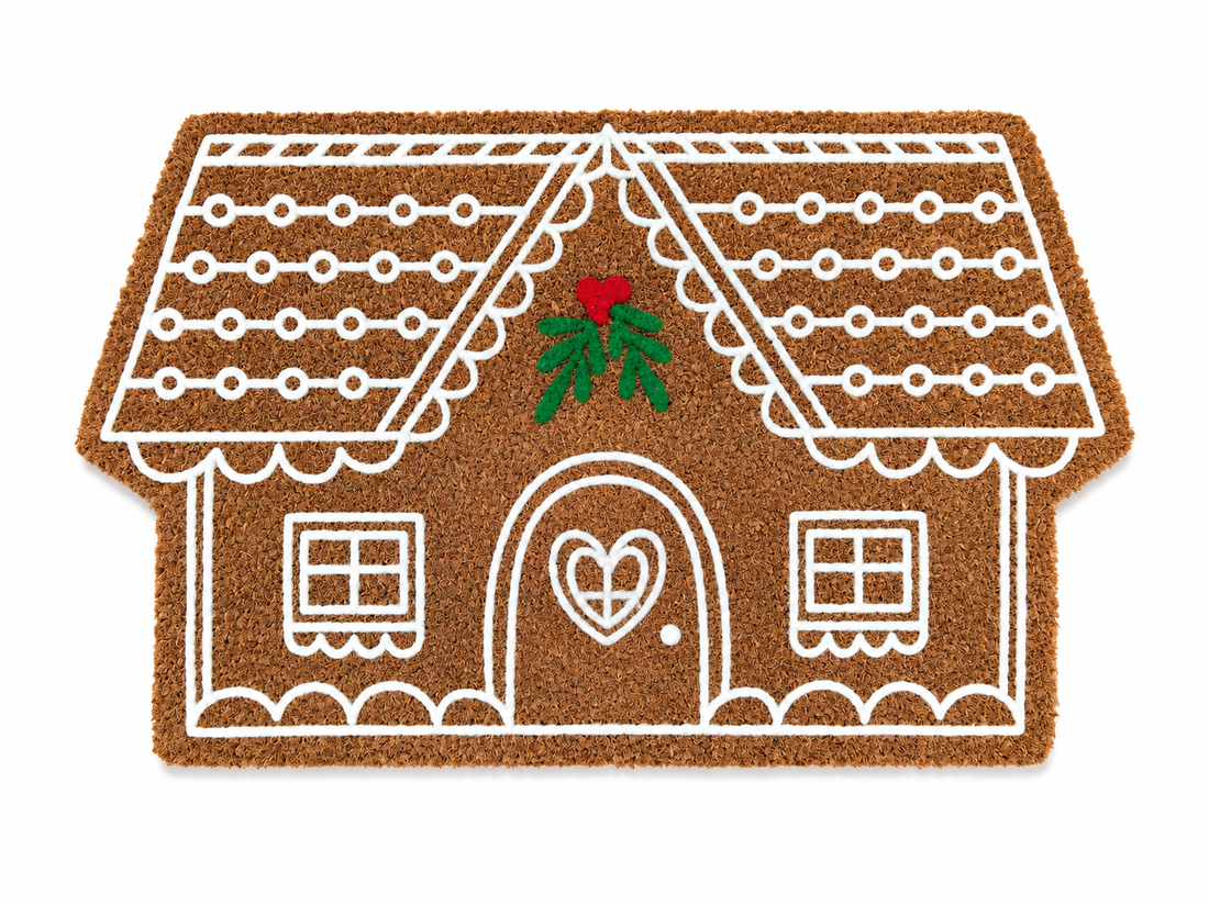 Gingerbread house-shaped doormat with a heart door and Christmas decorations on a white background