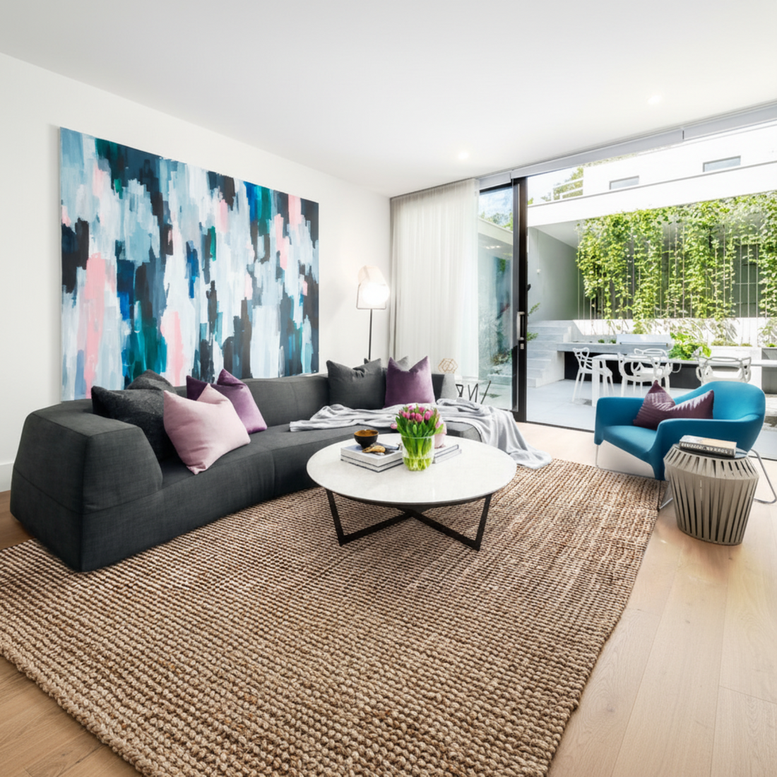 Modern living room with a gray sectional sofa, abstract wall art, and a coffee table.