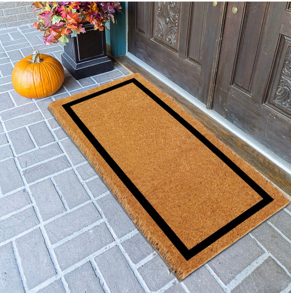 A long rectangle natural coir floor mat with a printed black border, placed on a doorstep.