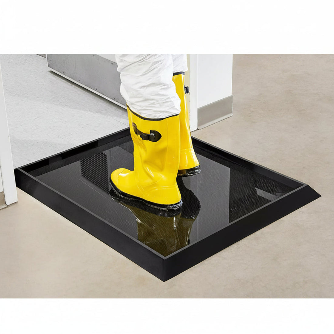 A person wearing yellow rubber boots steps onto a black floor mat with sanitising liquid.