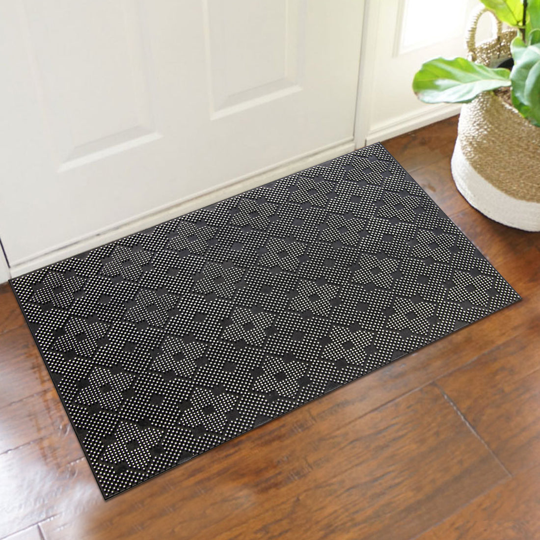 A black rubber pin floor mat with a geometric designer pattern, placed on a doorstep.