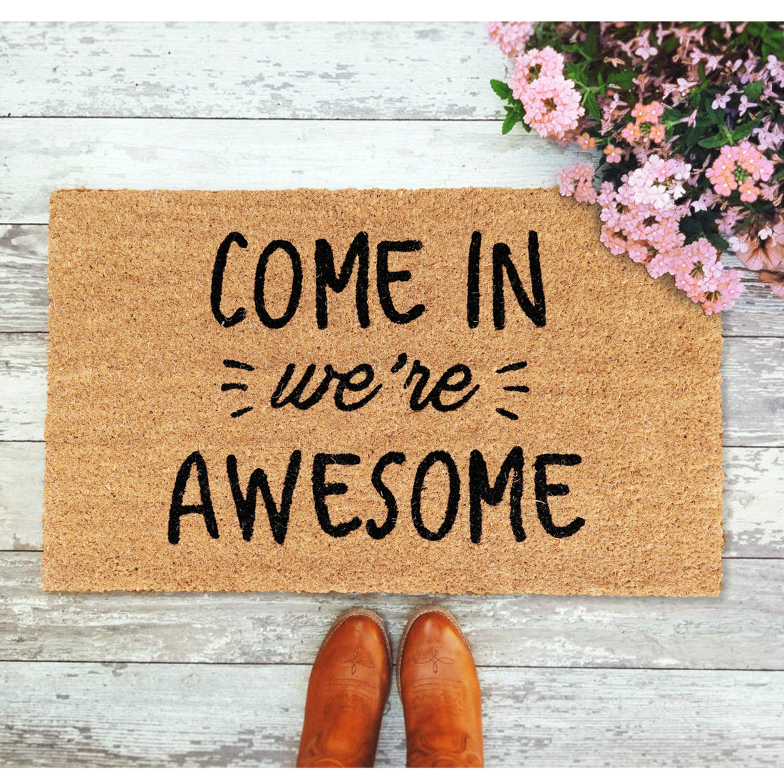 Rectangular natural coir entrance door mat with the humorous text 'COME IN WE'RE AWESOME' printed in black.