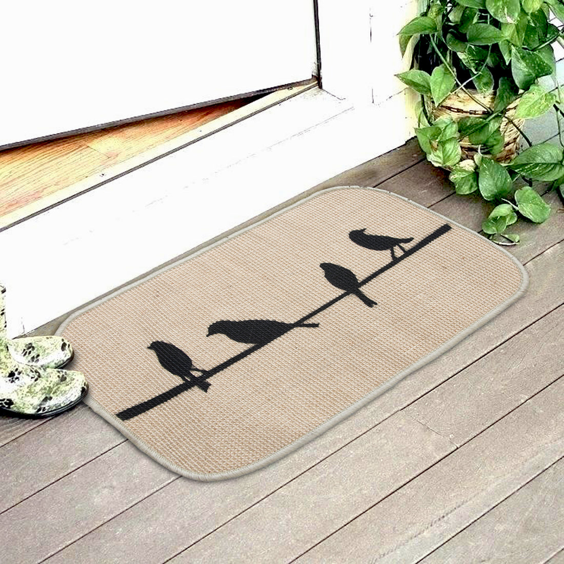 
                      
                        A beige jute floor mat with a bird design printed on it, placed on a doorstep, with birds perched on it.
                      
                    