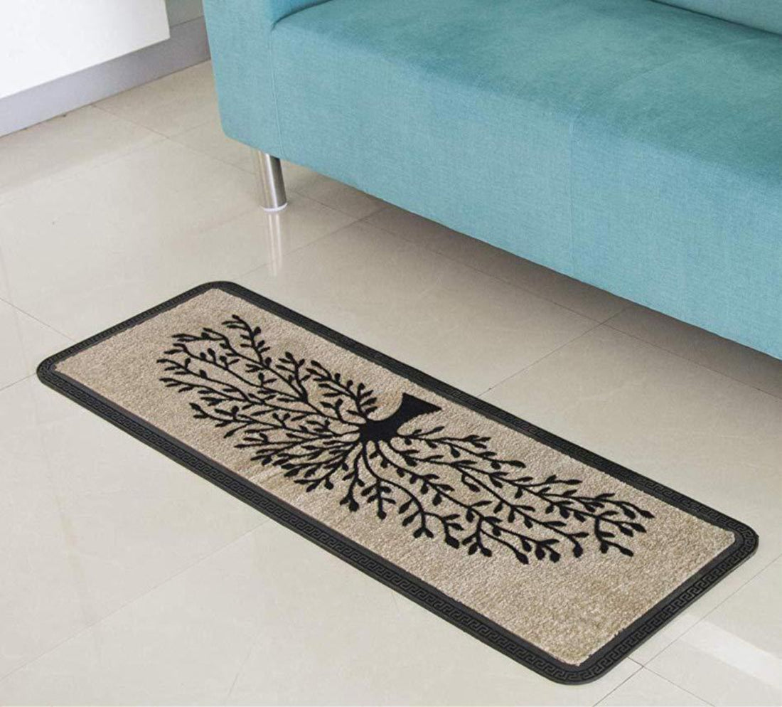A beige rectangular polypropylene floor mat with a tree design, placed on a tiled floor under a blue sofa.