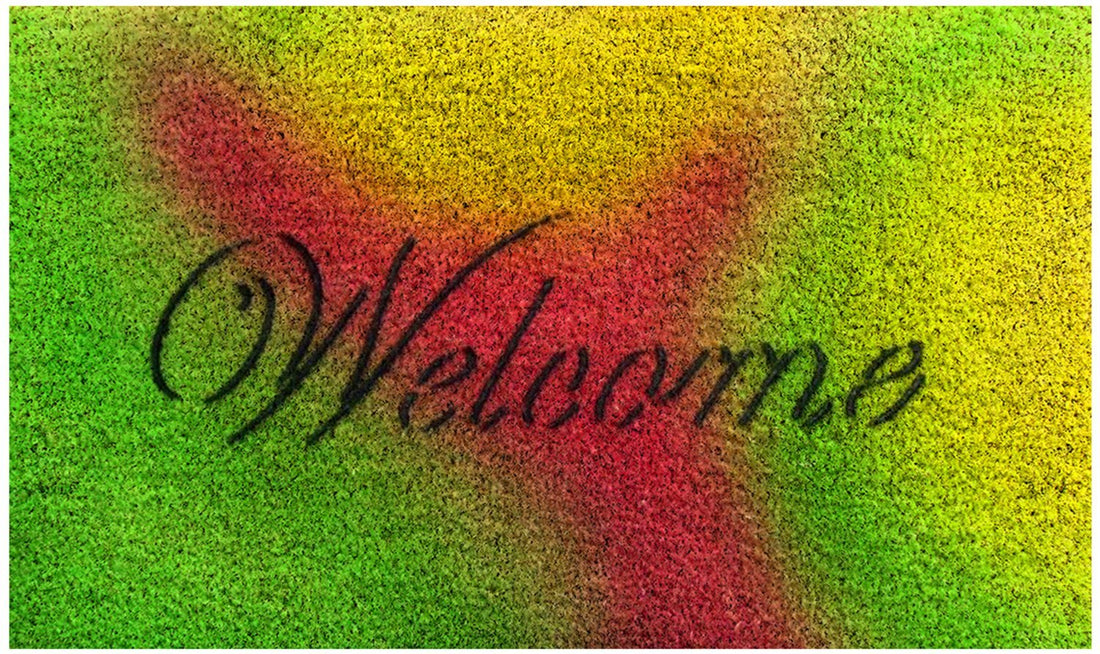 A rectangular natural coir door mat with a multicoloured 'Welcome' text design in red and green on a green background.