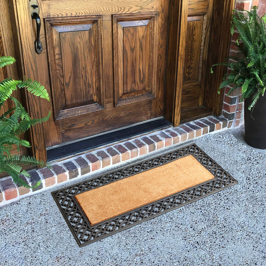 An oblong-shaped, coco rubber coir moulded door mat with a plain design, placed on a doorstep.