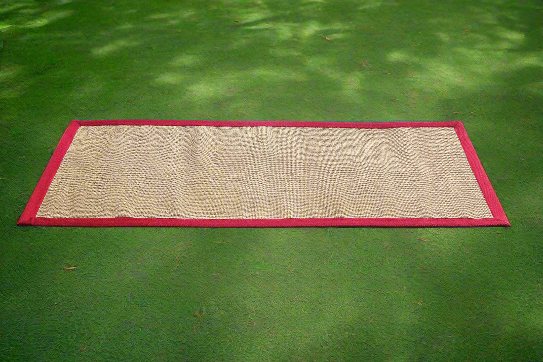 
                      
                        An anti-skid, eco-friendly jute yoga mat with a maroon cotton border, placed on a green floor.
                      
                    
