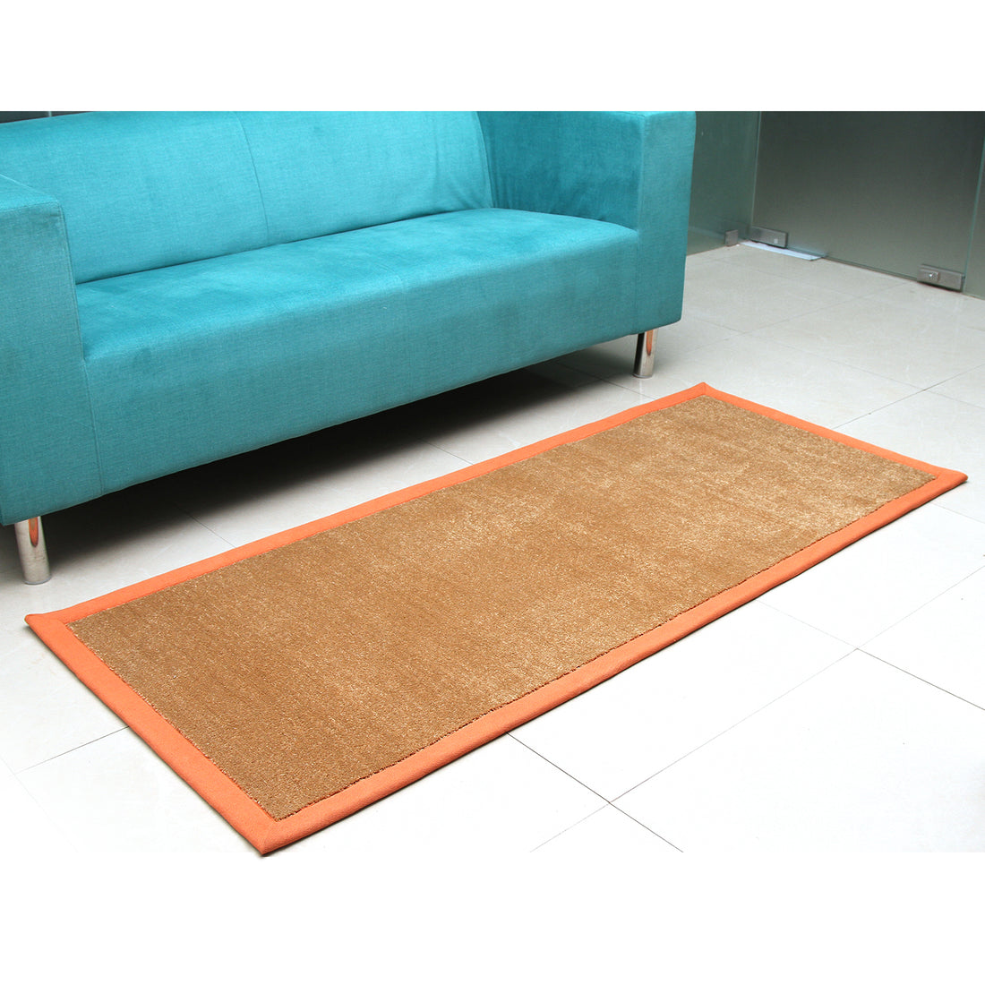 
                      
                        An oblong brown yoga mat with an orange border, placed on the floor beside a blue sofa.
                      
                    