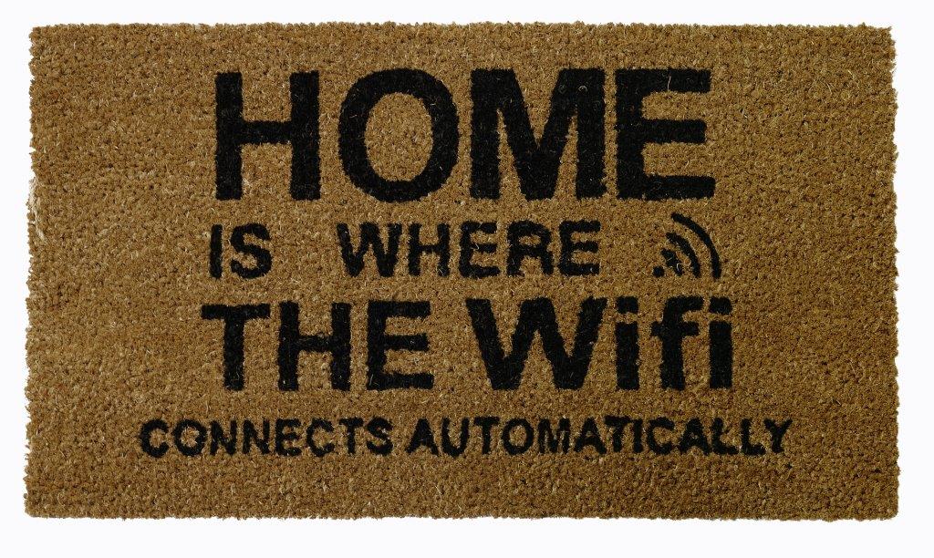 A rectangular beige coir floor mat with the text 'HOME IS WHERE THE WIFI CONNECTS AUTOMATICALLY' printed in black.