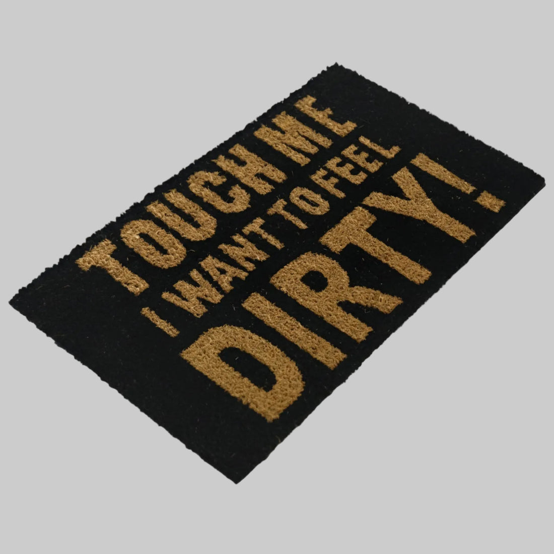 A black rectangular coir floor mat with the phrase 'TOUCH ME I WANT TO FEEL DIRTY!' printed in gold.