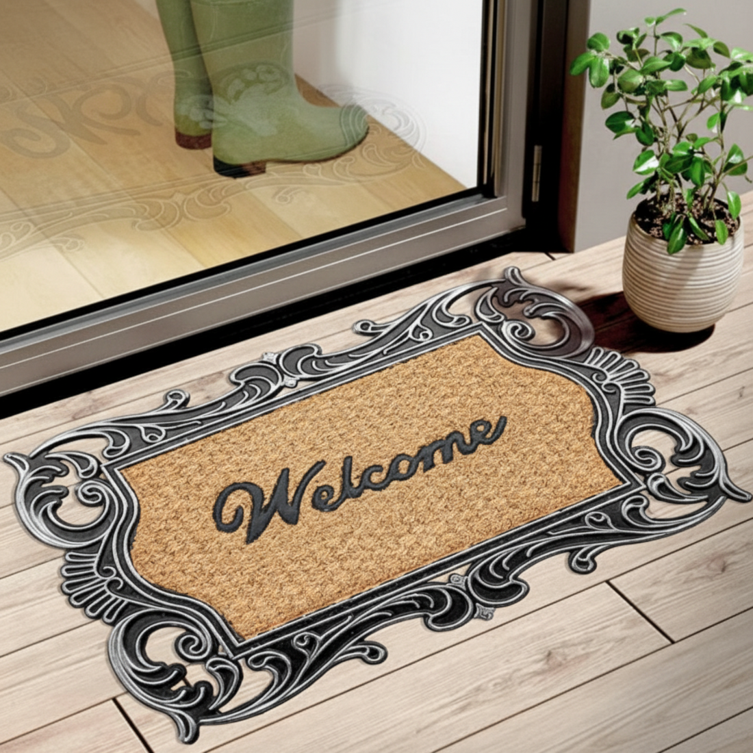 A rectangular doormat with a black and coir design, featuring the word 'WELCOME' in bold, placed on a wooden floor by a doorstep.