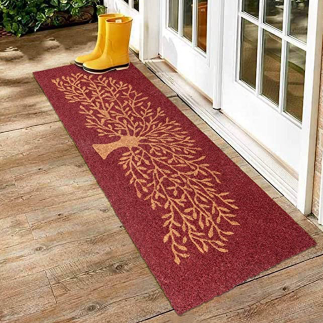 A brown rectangular OnlyMat with a Tree of Life printed design, placed on a wooden floor with yellow boots at the top left corner.