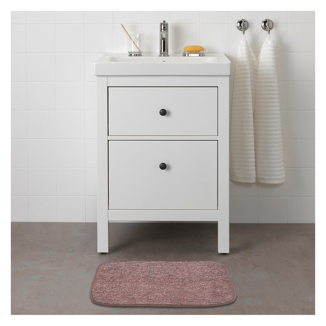 A plain brown rectangular mat placed on the floor in front of a white bathroom vanity.