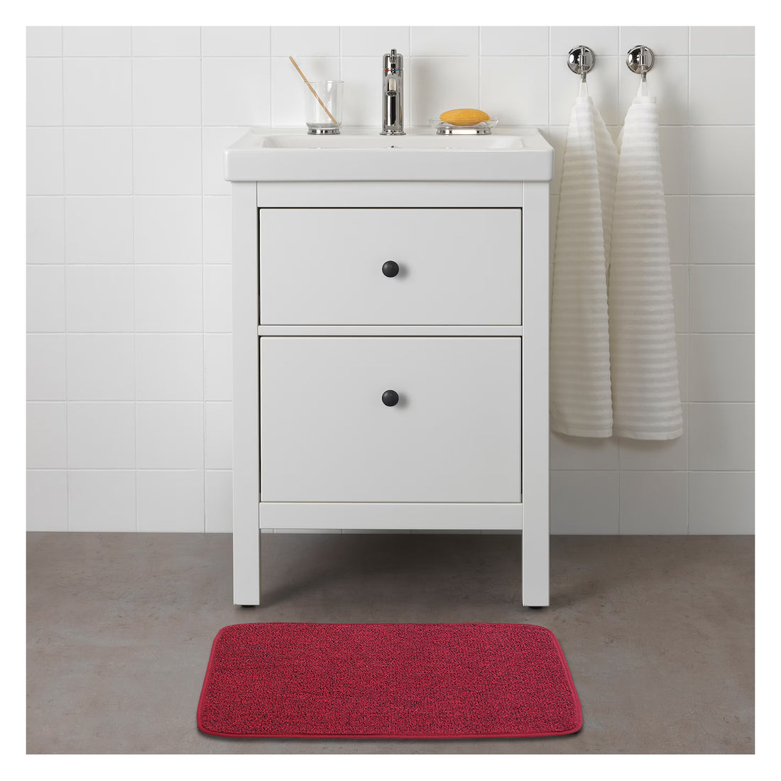
                      
                        A red rectangular mat with a textured surface is placed on the floor in front of a white cabinet.
                      
                    