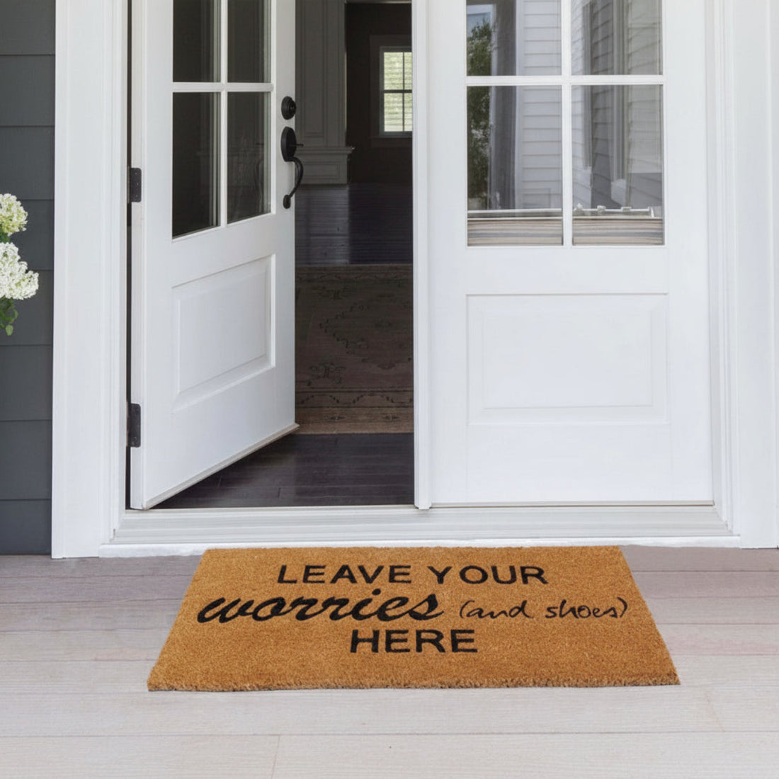 Coir Doormat with humorous text on a wooden floor in front of a white door.