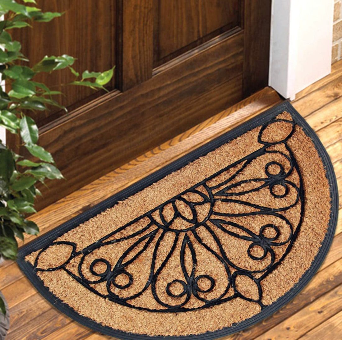 A half-moon-shaped coco rubber doormat with a rubber border featuring a decorative pattern, placed on a wooden floor.