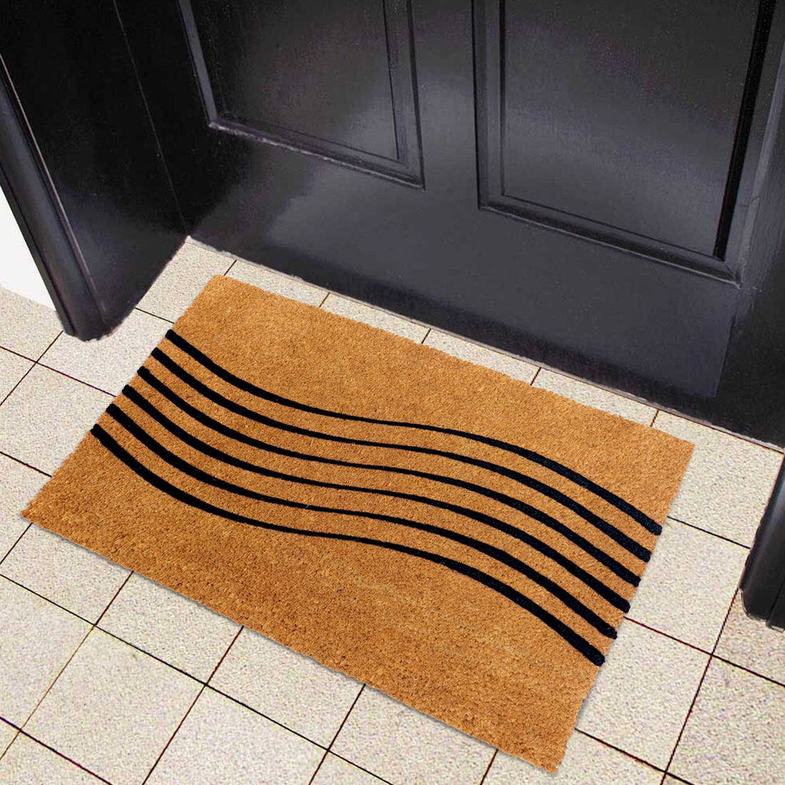 A coir doormat with black nylon flocking in a wave design, placed on a tiled floor in front of a door.