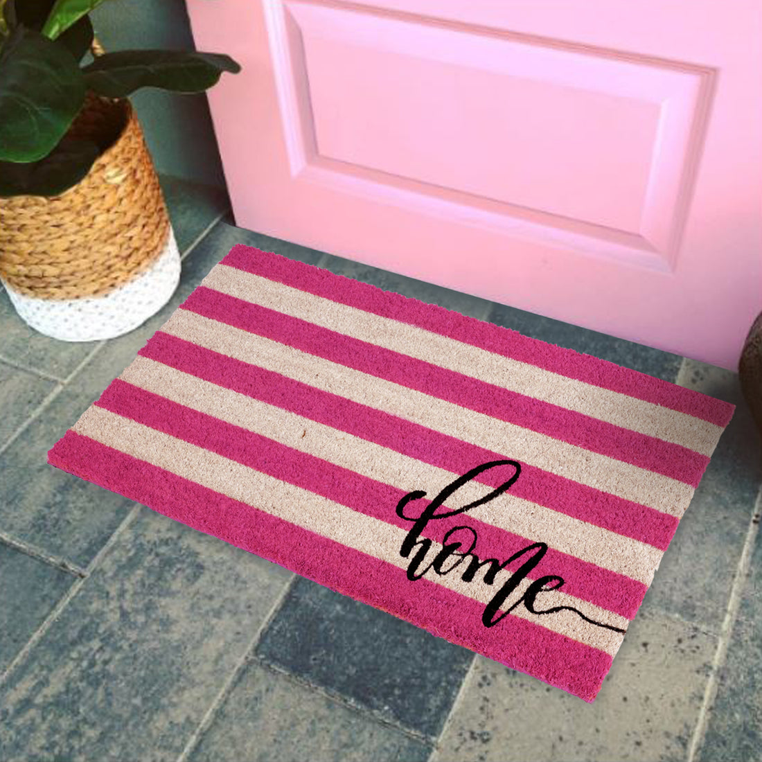 A rectangular natural coir door mat with a retro stripe design in pink and white, featuring the word 'Home' in a cursive script, placed on a doorstep.