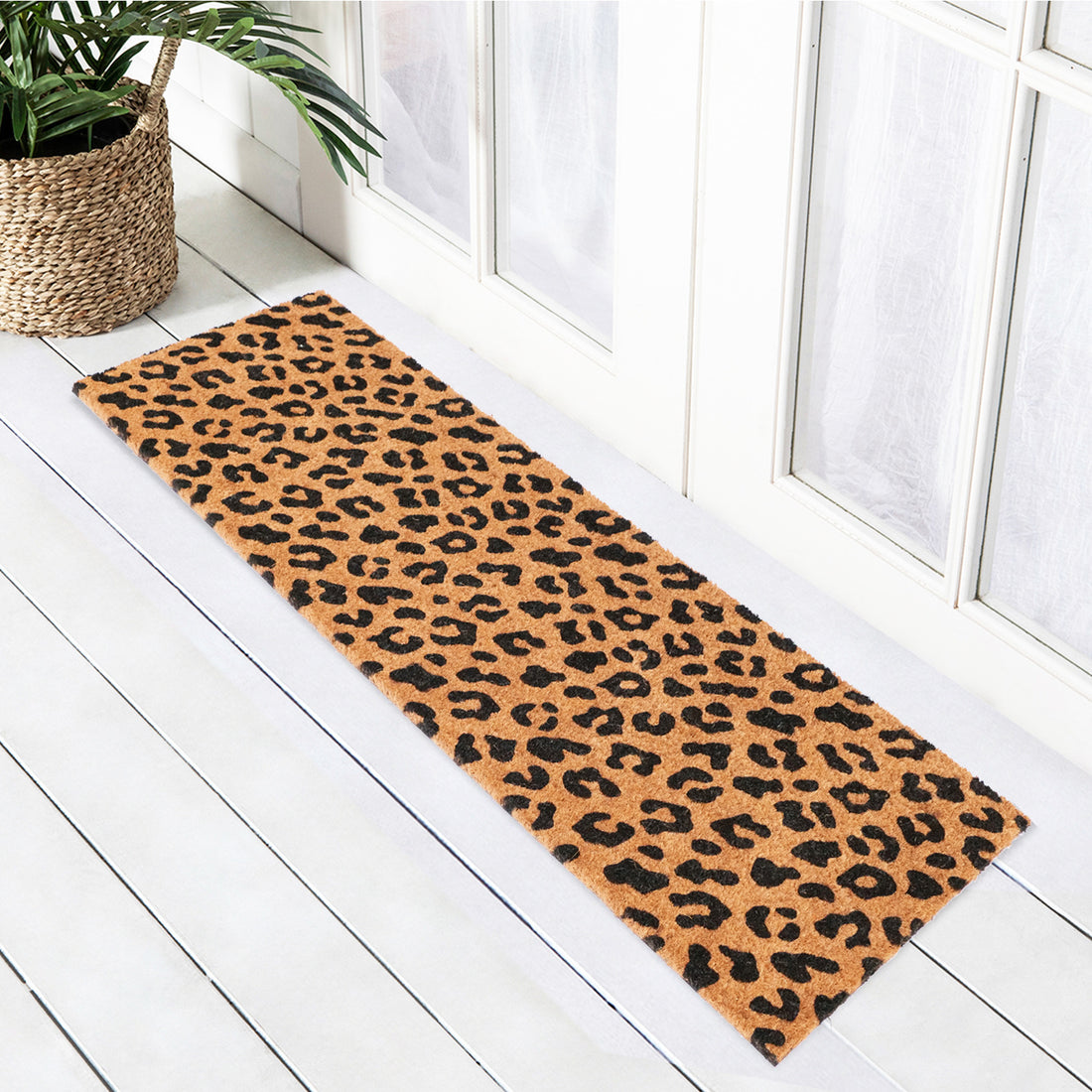 A leopard print natural coir oblong doormat placed on a wooden floor, with a durable vinyl back.