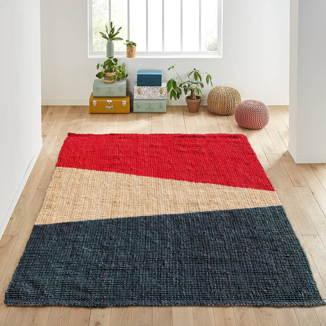 A rectangular jute rug with a geometric pattern featuring red, black, and bleach colours, placed on a wooden floor in a home setting.